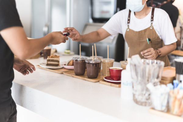 Focus on iced chocolate drink with waitress taking digital pagers form customer